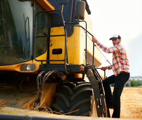 A farmer climbing into a tractor